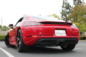 2018 Porsche 718 Cayman base in Carmine Red color photographed from a low, rear 3/4 angle