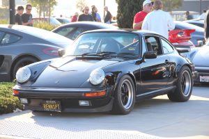 A classic Porsche 911 with roll bar and black Fuchs wheels