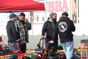 Four friends talk amongst each other at an import car show