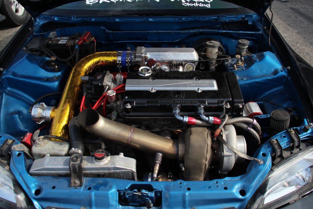 An engine bay of a Honda car, showing a B-series engine with a custom turbo setup