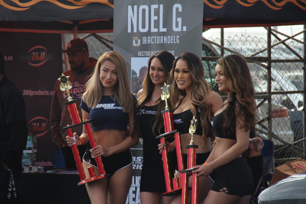 Four attractive import models pose with trophies at a car show