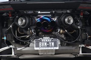 The engine bay of a twin turbo Lamborghini Huaracan, shown directly from the rear, showing the turbos, wastegates, and beautiful multi-colored titanium exhaust manifold