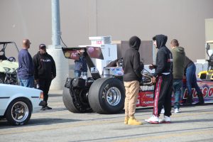 Fans stand around a Top Fuel dragster that waits in line to make a 1/4 mile pass