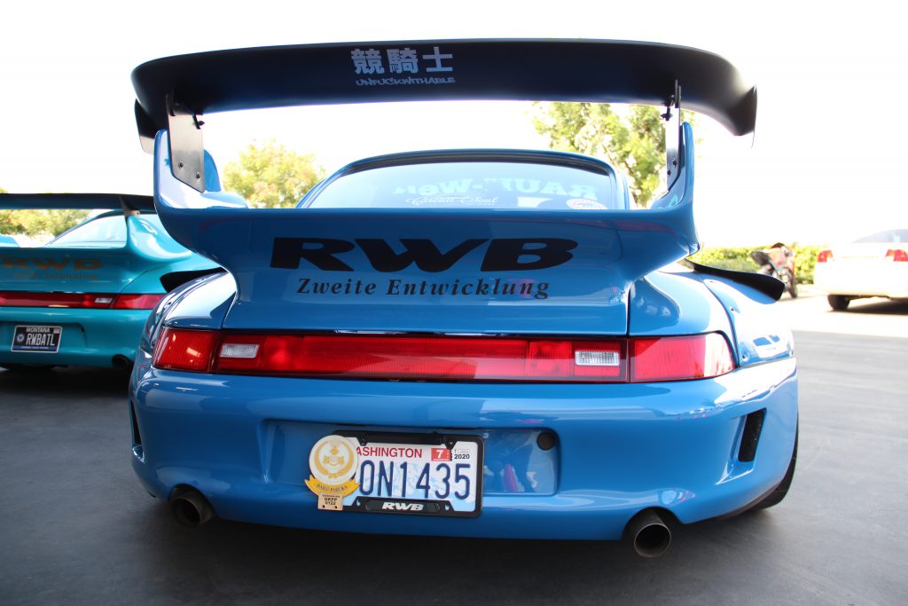 Rear photo of a blue RWB Porsche 993, emphasizing the massive rear wing.